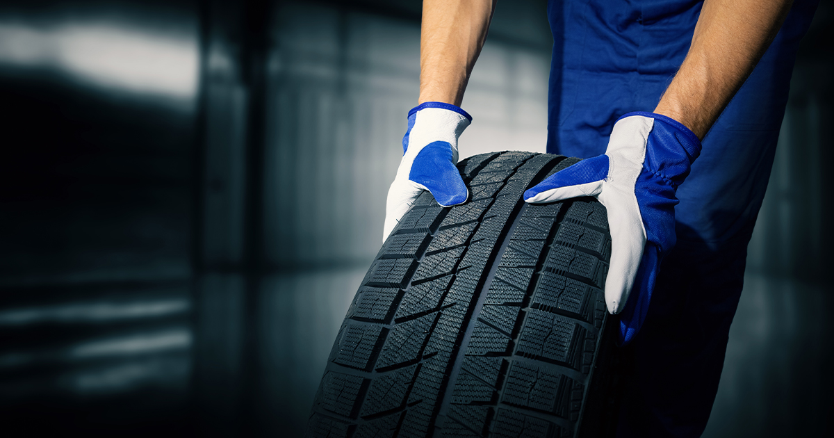 A close-up of a service technician's hands carrying a tire