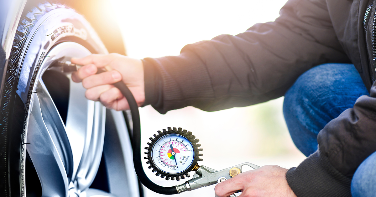 A close-up of a person holding a tire pressure gauge checking their tire's air pressure